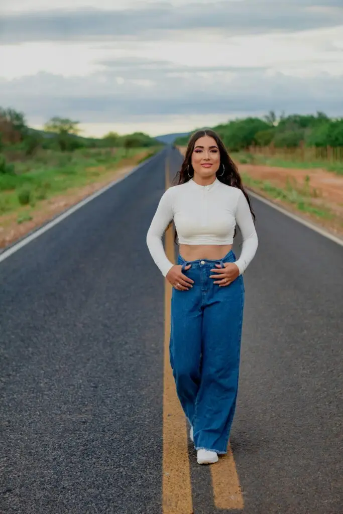 The Dos and Don'ts of Styling Wide Leg Jeans: Chic and Casual Options A young woman in trendy wide-leg jeans and crop top walking confidently on a rural road.
