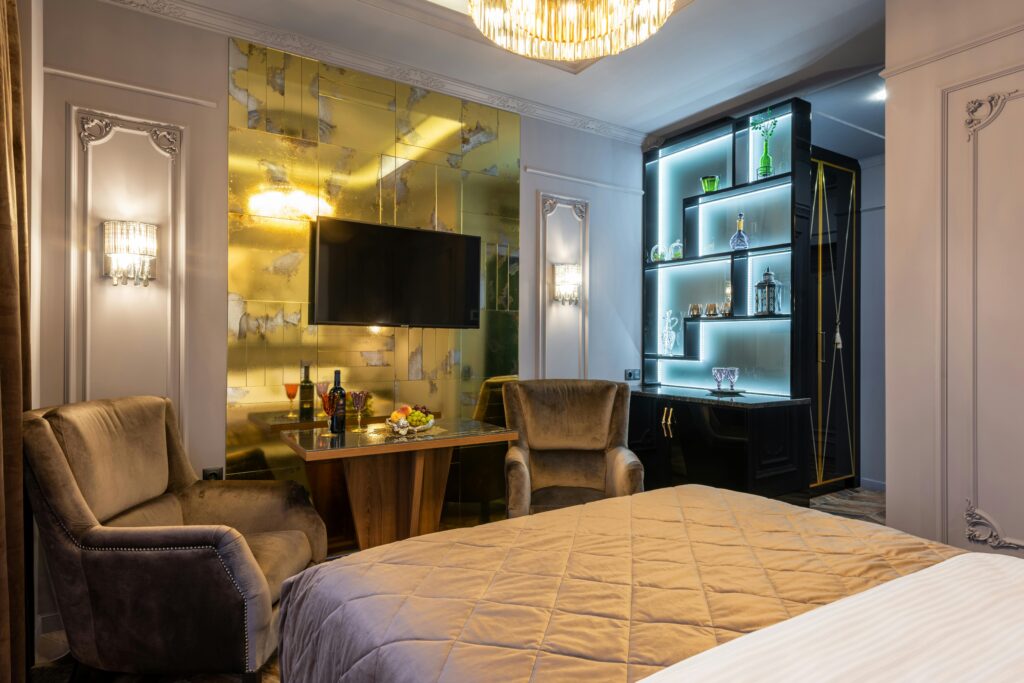 A sophisticated hotel room featuring modern decor, velvet chairs, and a sleek television setup.